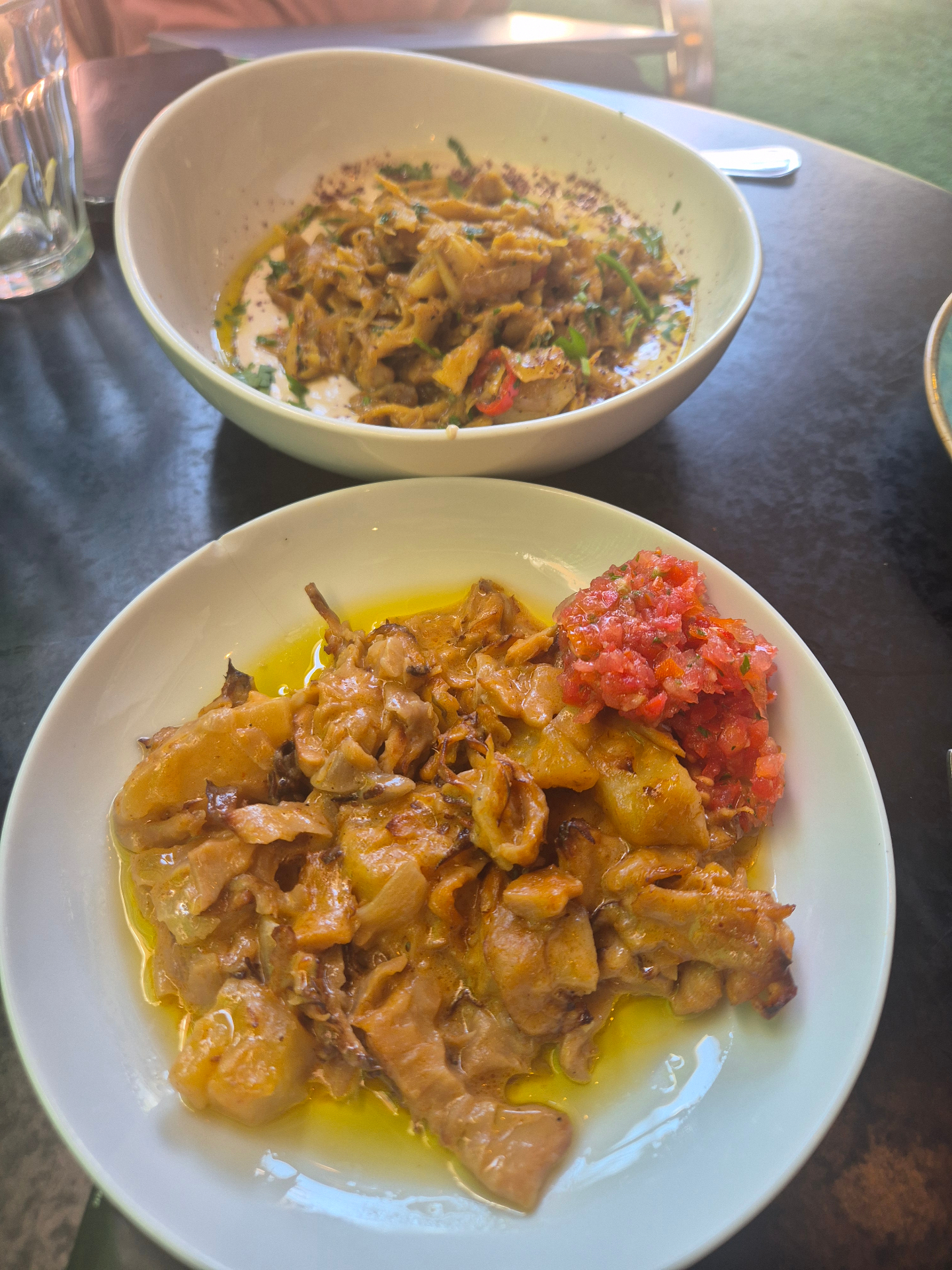 Two restaurant plates of Provero with tahini, herbs and tomato salsa